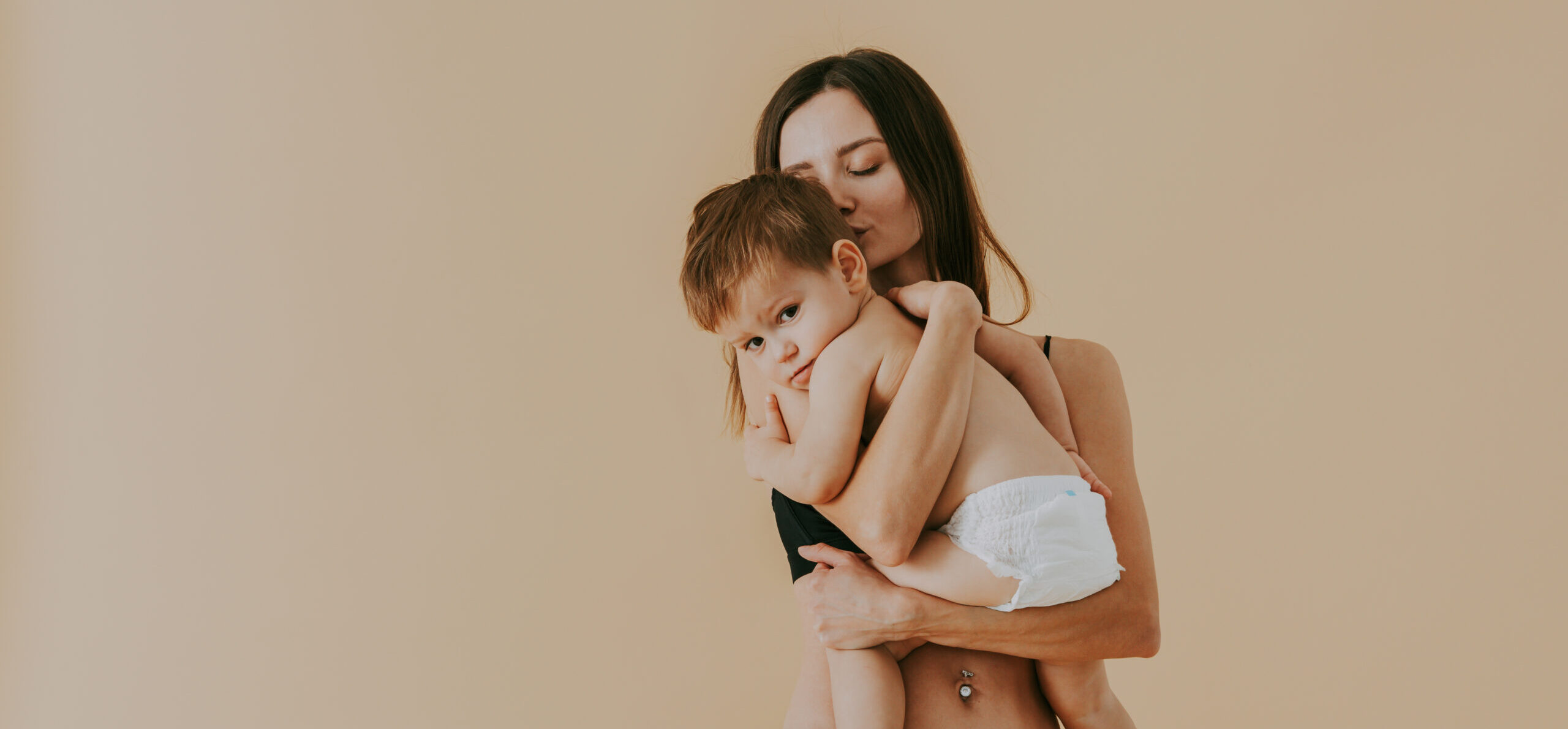 Happy woman holding her baby on colored background - Young woman wearing underwear taking care of her little son - Pregnancy, motherhood, people and expectation concept